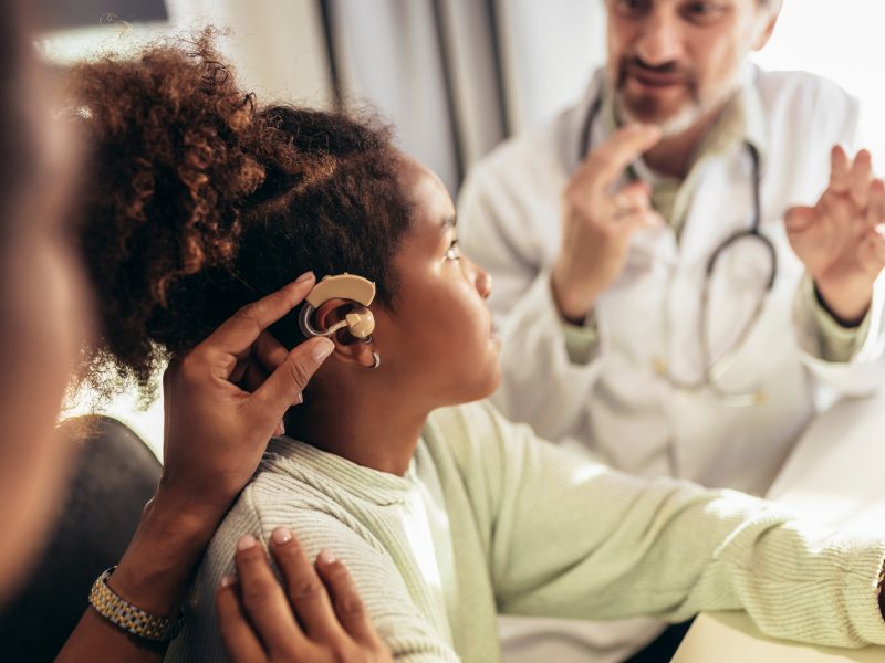 Smiling,Deaf,African,American,Girl,With,Ear,Implant,At,Doctor's