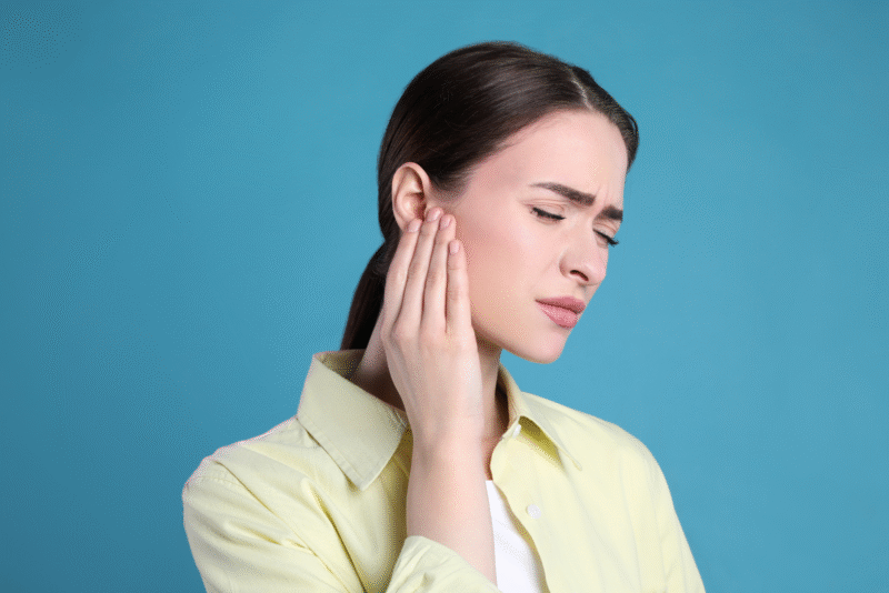 woman holding ear in pain