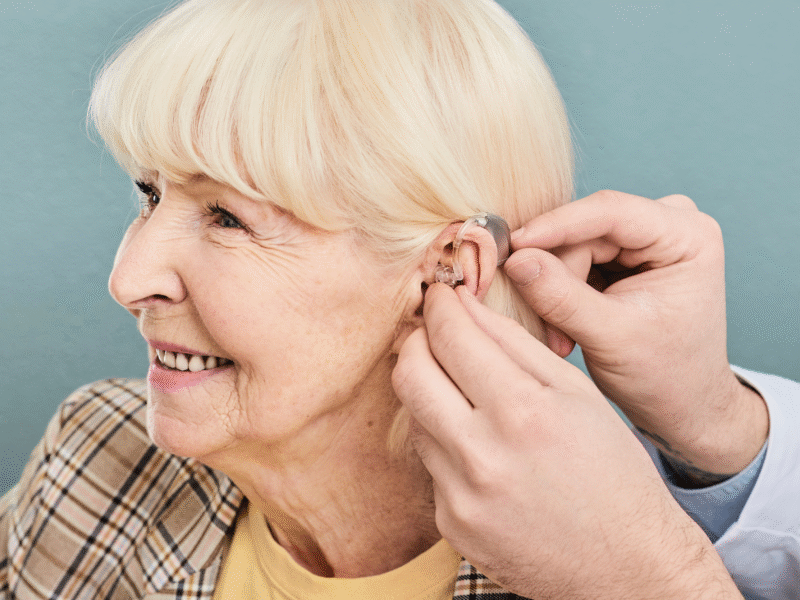 Woman smiling while getting hearing aid fitted
